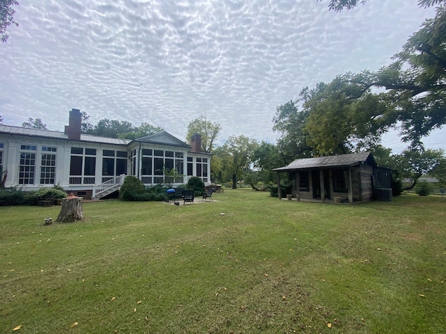 view of yard with a sunroom and an outbuilding