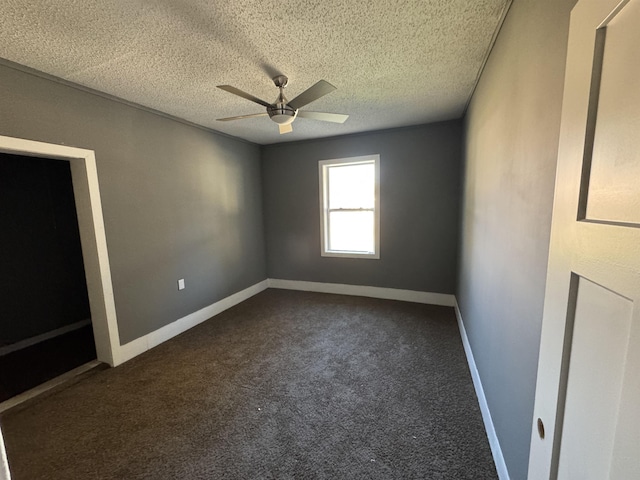 unfurnished room with ceiling fan, dark carpet, and a textured ceiling