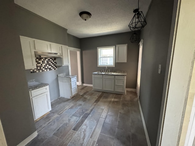 kitchen featuring white cabinetry, sink, dark hardwood / wood-style floors, a textured ceiling, and decorative light fixtures