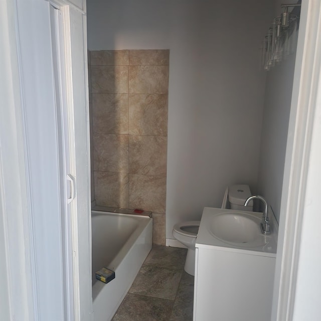 bathroom with vanity, toilet, and a tub