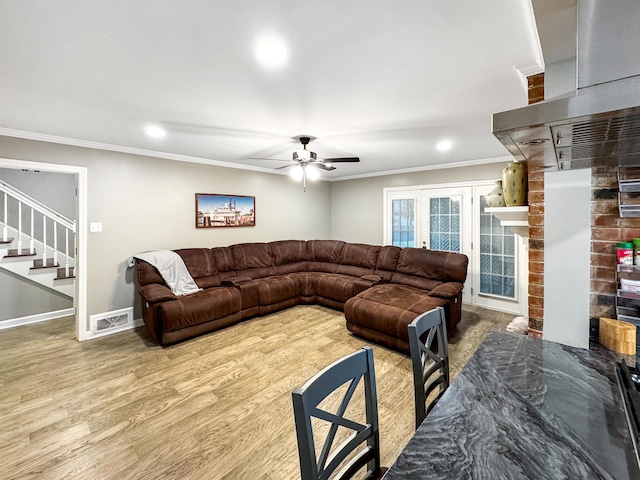 living room with hardwood / wood-style floors, ceiling fan, ornamental molding, and a brick fireplace