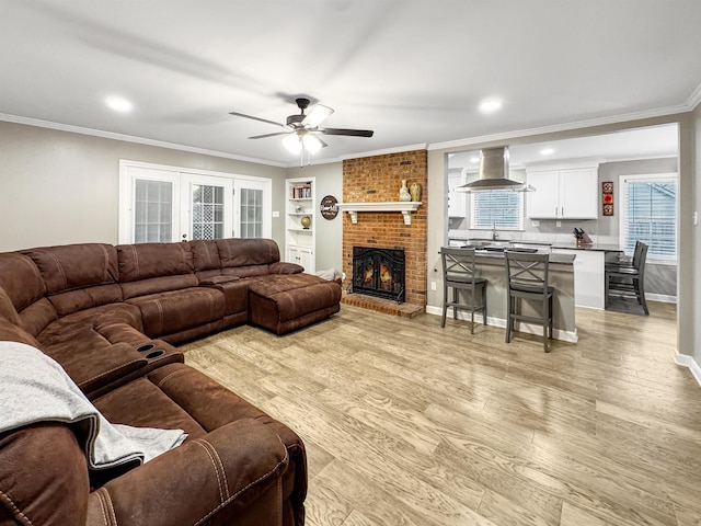 living room featuring a fireplace, ceiling fan, light hardwood / wood-style flooring, and ornamental molding