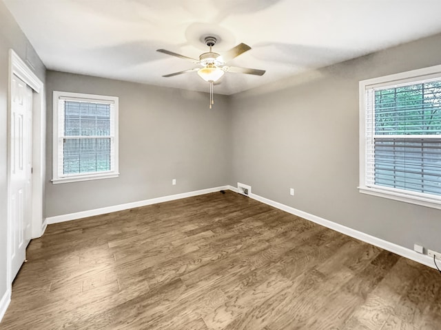 empty room featuring dark hardwood / wood-style floors, plenty of natural light, and ceiling fan