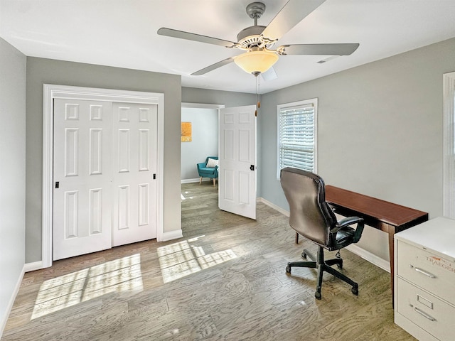 home office with light hardwood / wood-style flooring and ceiling fan