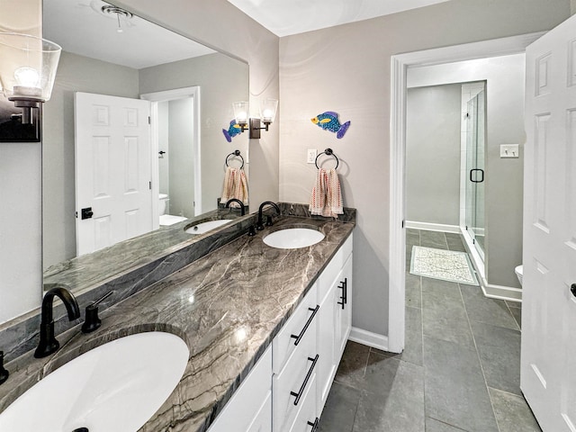 bathroom with tile patterned flooring, vanity, toilet, and a shower with shower door