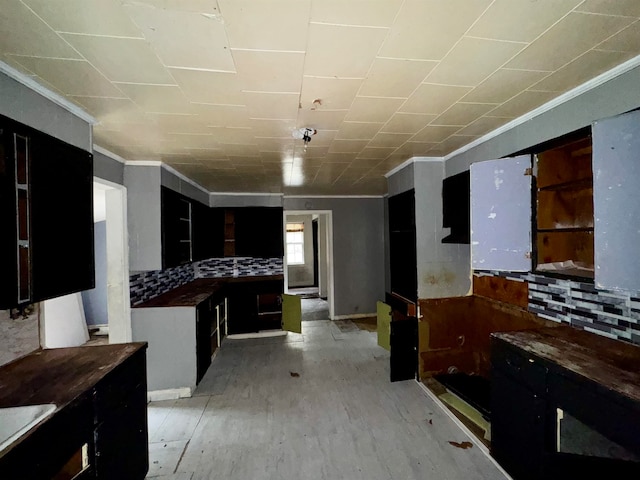 kitchen featuring backsplash, light hardwood / wood-style flooring, and ornamental molding