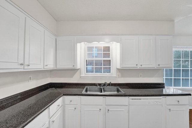 kitchen featuring white cabinetry, dishwasher, dark stone counters, and sink