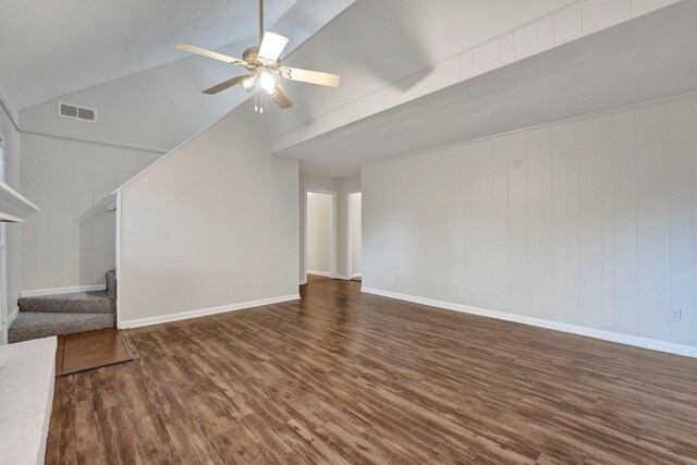 unfurnished living room with wooden walls, dark hardwood / wood-style floors, ceiling fan, and lofted ceiling