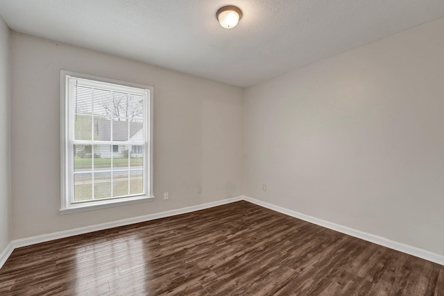 spare room featuring a textured ceiling and dark hardwood / wood-style floors