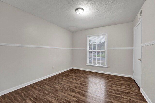 empty room with dark hardwood / wood-style floors and a textured ceiling