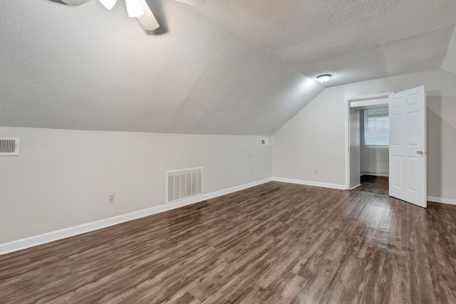 additional living space featuring a textured ceiling, lofted ceiling, ceiling fan, and dark hardwood / wood-style floors