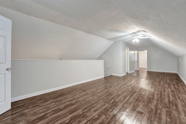 bonus room featuring a textured ceiling, ceiling fan, dark wood-type flooring, and vaulted ceiling