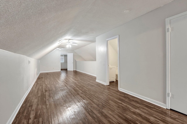 additional living space featuring a textured ceiling, vaulted ceiling, and dark wood-type flooring