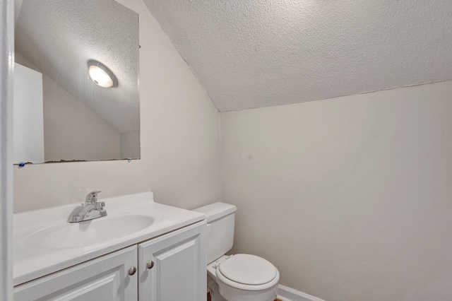 bathroom with a textured ceiling, vanity, vaulted ceiling, and toilet