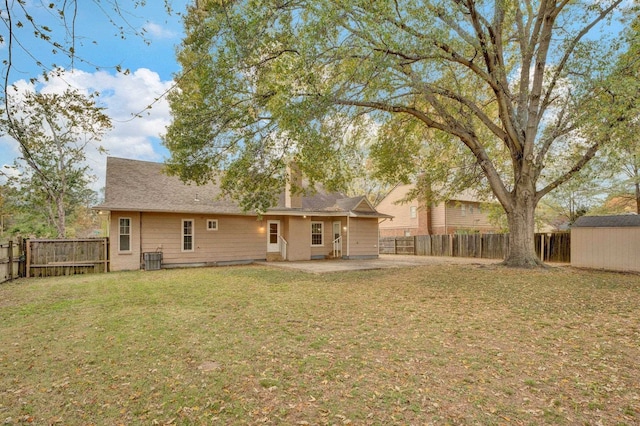 back of property with a lawn, a patio, and a shed