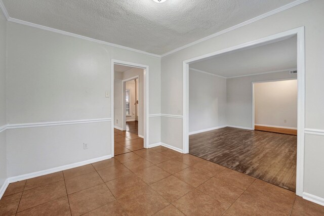 unfurnished room with hardwood / wood-style floors, a textured ceiling, and ornamental molding