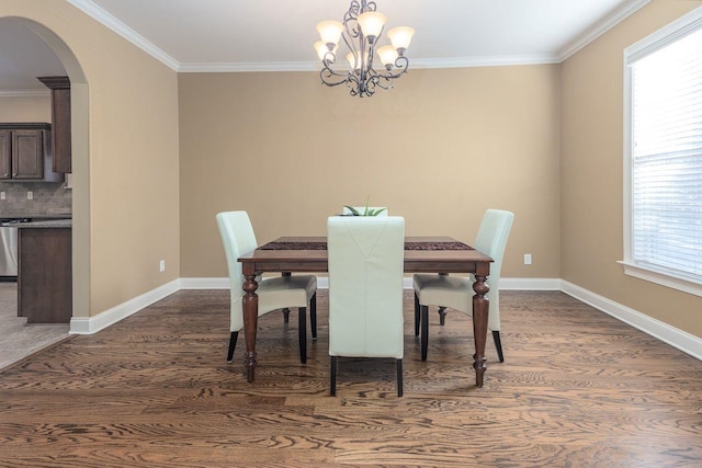 dining room featuring dark hardwood / wood-style floors, a healthy amount of sunlight, ornamental molding, and a chandelier