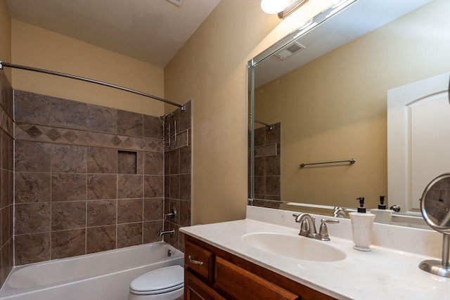 full bathroom featuring vanity, tiled shower / bath combo, and toilet