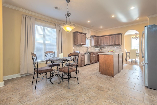 kitchen with decorative backsplash, ornamental molding, stainless steel appliances, a center island, and hanging light fixtures