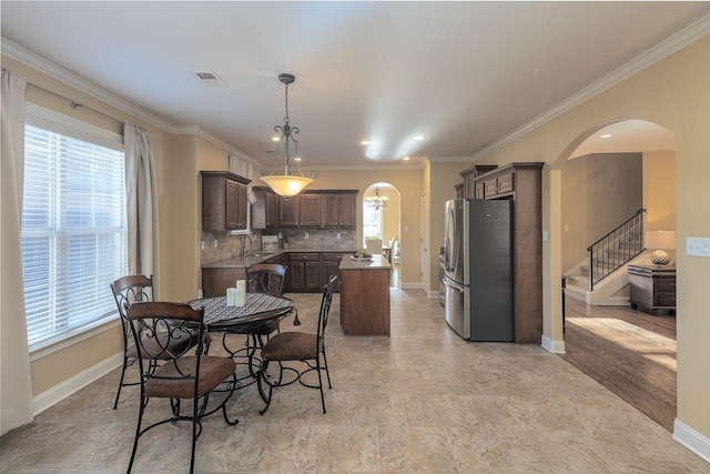 dining room with a healthy amount of sunlight, ornamental molding, and sink