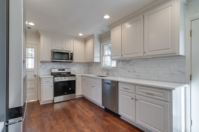 kitchen featuring decorative backsplash, stainless steel appliances, dark wood-type flooring, sink, and white cabinets