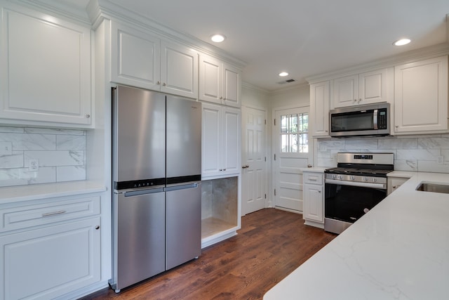 kitchen featuring tasteful backsplash, stainless steel appliances, crown molding, dark hardwood / wood-style floors, and white cabinetry