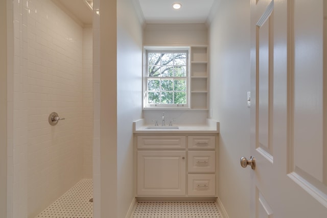 bathroom with crown molding, vanity, and tiled shower