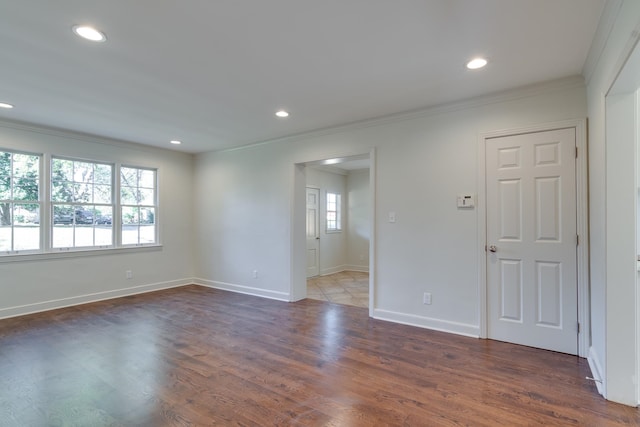 spare room with crown molding and dark wood-type flooring