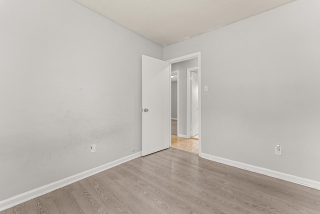 unfurnished room with a textured ceiling and light wood-type flooring