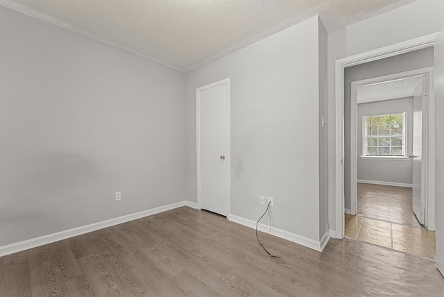 spare room featuring light wood-type flooring and a textured ceiling