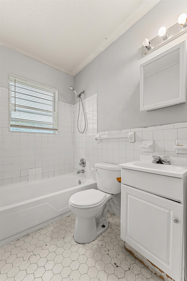 full bathroom with vanity, toilet, tile walls, and tiled shower / bath combo