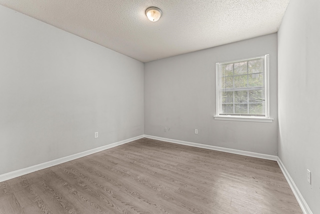 unfurnished room with a textured ceiling and light hardwood / wood-style flooring