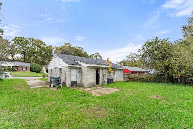 rear view of house featuring central AC and a yard