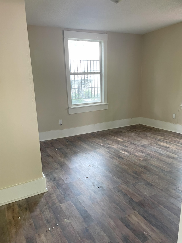 empty room with a textured ceiling and dark hardwood / wood-style floors