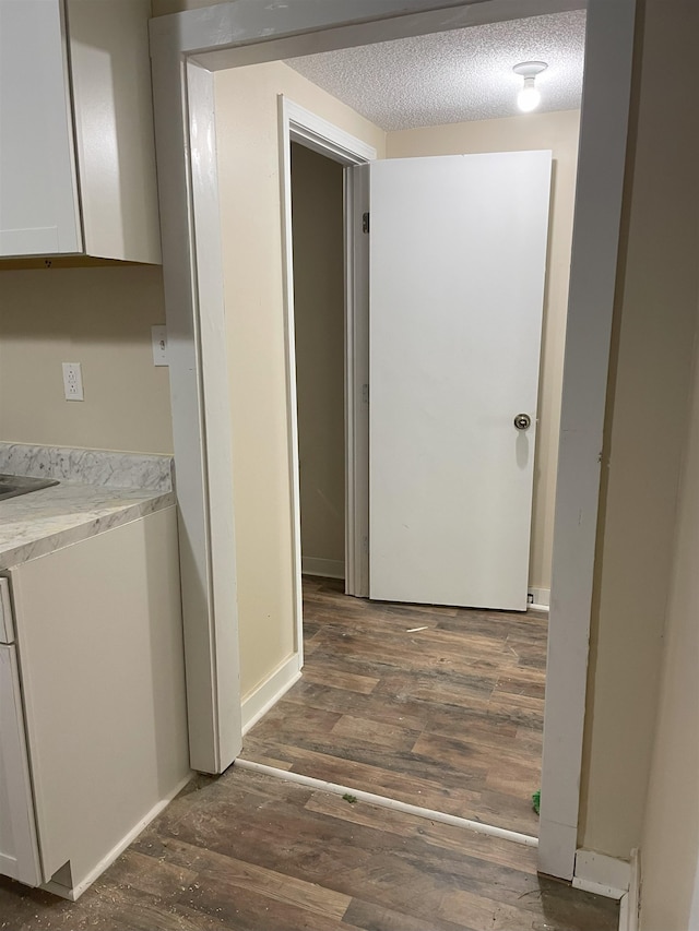 corridor with a textured ceiling and dark hardwood / wood-style floors