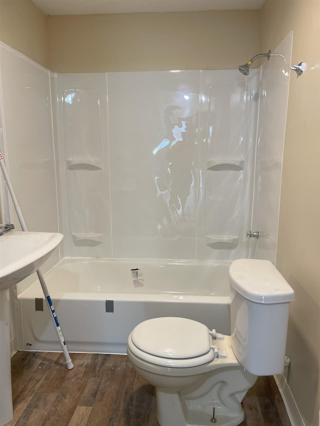 bathroom with washtub / shower combination, toilet, and wood-type flooring