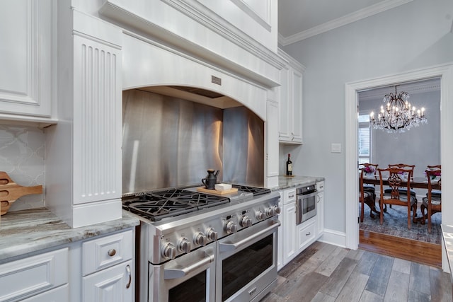 kitchen with white cabinets, crown molding, light stone countertops, appliances with stainless steel finishes, and light hardwood / wood-style floors