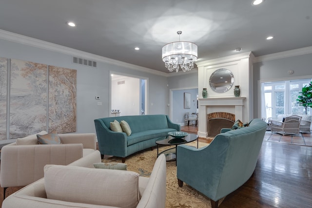 living room featuring a notable chandelier, wood-type flooring, ornamental molding, and a brick fireplace