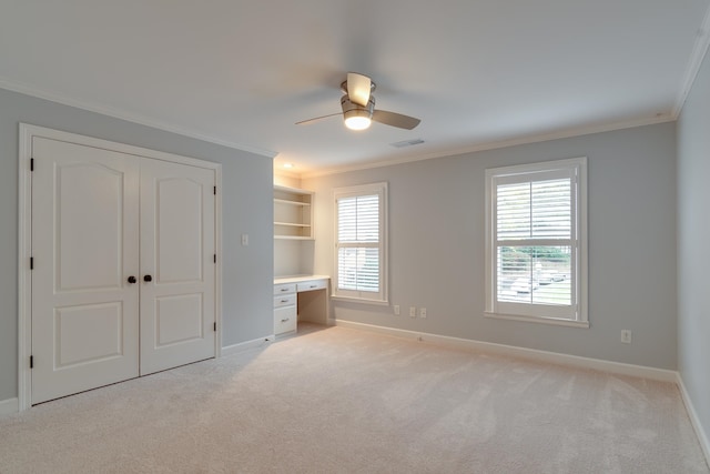 unfurnished bedroom featuring ceiling fan, crown molding, light carpet, and a closet