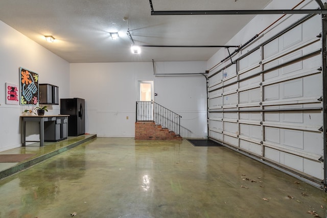 garage featuring black fridge with ice dispenser