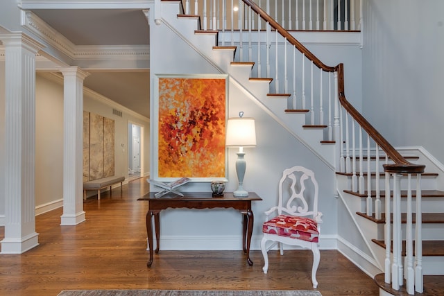 stairway with wood-type flooring, ornamental molding, and decorative columns