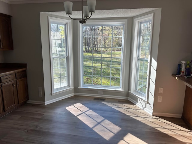 unfurnished dining area featuring a chandelier, dark hardwood / wood-style floors, and a wealth of natural light