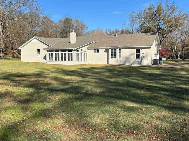 rear view of property with a sunroom, central AC unit, and a lawn