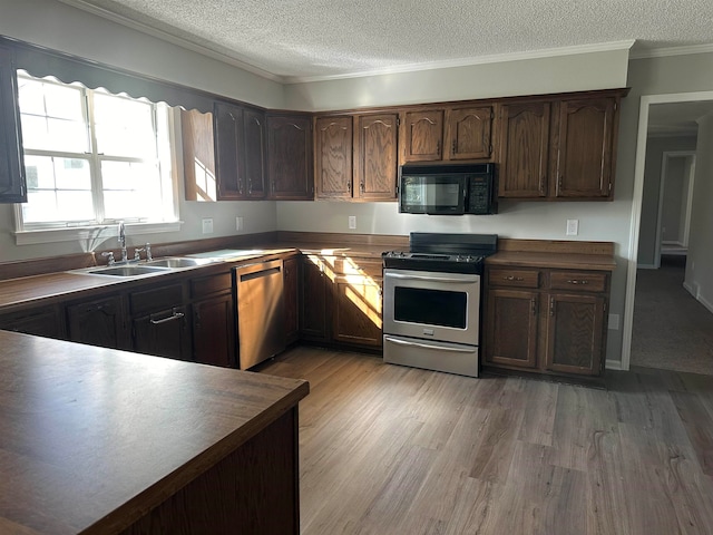 kitchen featuring sink, stainless steel appliances, light hardwood / wood-style flooring, a textured ceiling, and ornamental molding