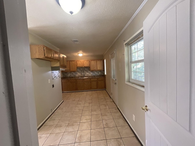 kitchen with decorative backsplash, a textured ceiling, crown molding, sink, and light tile patterned flooring