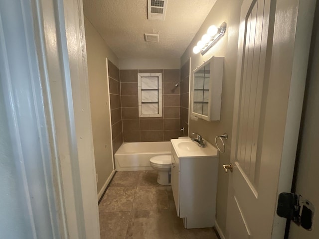 full bathroom featuring vanity, tile patterned floors, tiled shower / bath combo, toilet, and a textured ceiling