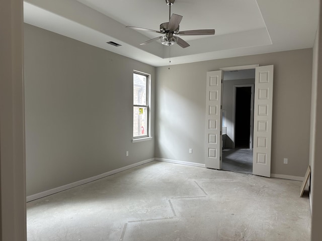 unfurnished bedroom featuring baseboards, visible vents, concrete floors, and a raised ceiling