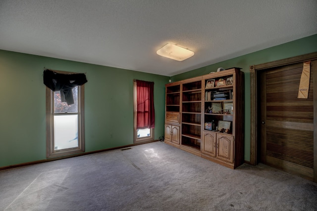 unfurnished room with a textured ceiling and light carpet