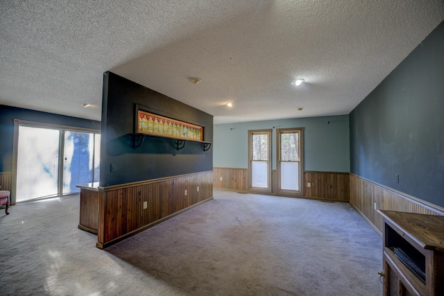 unfurnished living room with light colored carpet and a textured ceiling