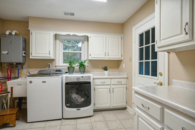 washroom featuring sink, cabinets, washing machine and dryer, water heater, and light tile patterned floors